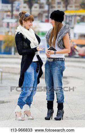 Two young women are chatting on the street View Large Photo Image Stock Image - Two young women are chatting on the street. Fotosearch
