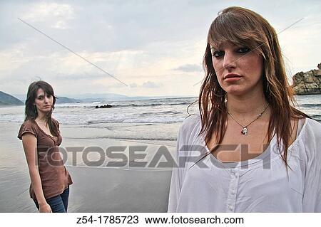 Stock Image - Two young women at El Sabl? n beach, Asturias, Spain. Fotosearch