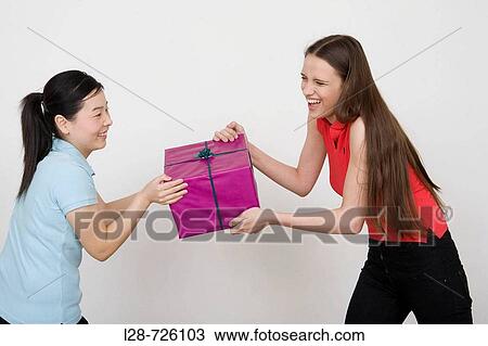 Stock Image - Two young women holding gift. Fotosearch