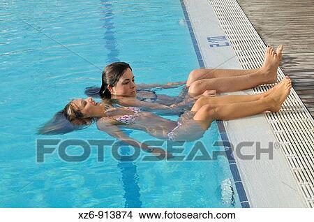 Two young women in the swimming pool, legs out of water View Large Photo Image Picture - Two young women in the swimming pool, legs out of water. Fotosearch