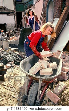 two young women in working gear performing manual labour on a building site loading rubble into wheelbarrows View Large Photo Image Stock Image - two young women in working gear performing manual labour on a building site loading rubble into wheelbarrows. Fotosearch