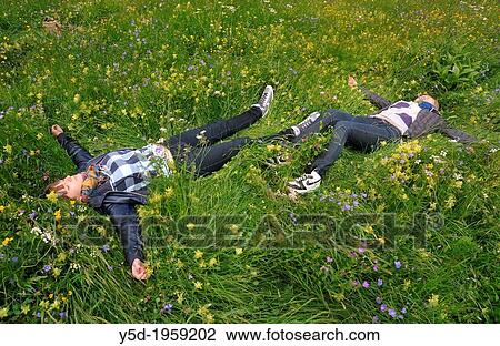 two young women laying with open arms, resting in the grass full of wildflowers, Saas Fee, Switzerland, canton Valais, caton Wallis View Large Photo Image Stock Image - two young women laying with open arms, resting in the grass full of wildflowers, Saas Fee, Switzerland, canton Valais, caton Wallis. Fotosearch