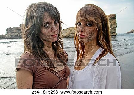 Stock Photo - Two young women on the beach, with sand on their face, El Sablon, Asturias, Spain. Fotosearch