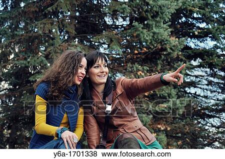 Two young women outdoors laughing and pointing View Large Photo Image Stock Photo - Two young women outdoors laughing and pointing. Fotosearch