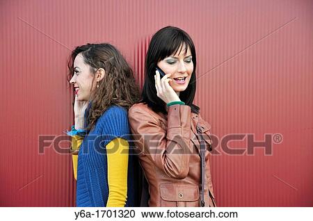 Two young women outdoors talking on cell phone View Large Photo Image Stock Image - Two young women outdoors talking on cell phone. Fotosearch