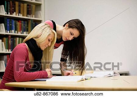 Two young women studying together in a university library View Large Photo Image Stock Photograph - Two young women studying together in a university library. Fotosearch
