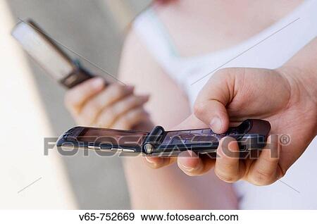 Stock Photo - two young women texting on their mobile phones. Fotosearch
