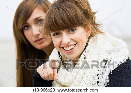 Two young women together, one is pointing at the camera View Large Photo Image Stock Image - Two young women together, one is pointing at the camera. Fotosearch