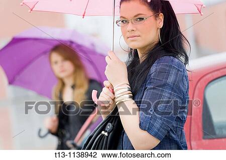 Stock Image - Two young women under umbrellas. Fotosearch