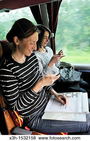 two young women using mobile phone in a bus County of Troms, Norway, Northern Europe View Large Photo Image Stock Photo - two young women using mobile phone in a bus County of Troms, Norway, Northern Europe. Fotosearch