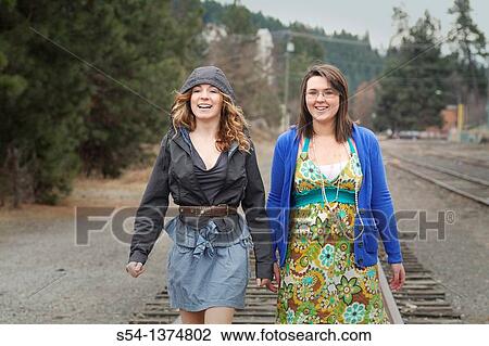 Two young women walking together on railroad tracks View Large Photo Image Stock Image - Two young women walking together on railroad tracks. Fotosearch