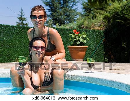 two young women with a glass of wine in a swimming pool View Large Photo Image Stock Image - two young women with a glass of wine in a swimming pool. Fotosearch