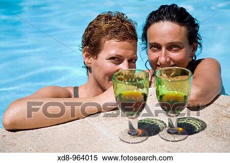 Stock Photography - two young women with a glass of wine in a swimming pool. Fotosearch