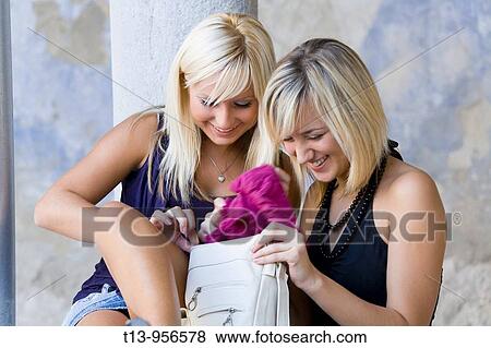 Two young women with a piece of fancy clothing taken from a purse View Large Photo Image Stock Photo - Two young women with a piece of fancy clothing taken from a purse. Fotosearch