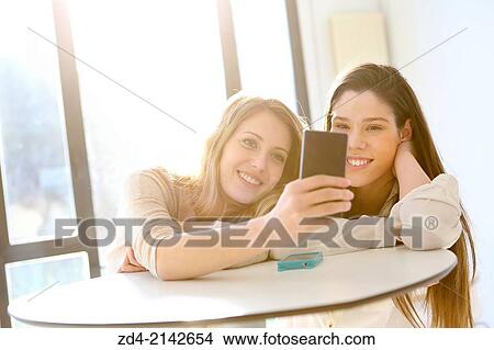 Picture - Two young women with smartphones. Fotosearch