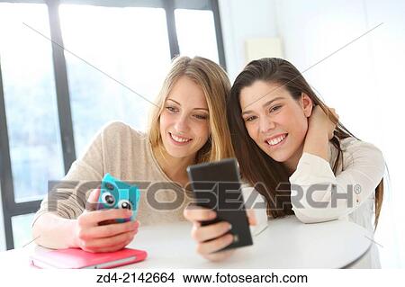 Two young women with smartphones View Large Photo Image Picture - Two young women with smartphones. Fotosearch
