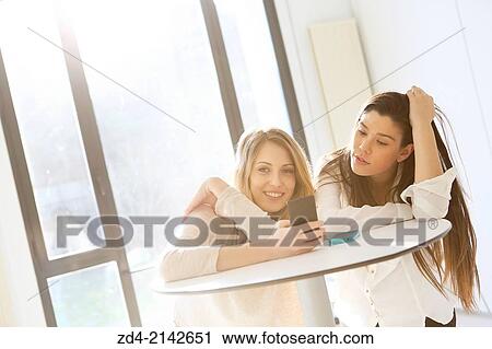 Two young women with smartphones View Large Photo Image Stock Image - Two young women with smartphones. Fotosearch