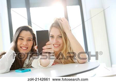 Two young women with smartphones View Large Photo Image Stock Image - Two young women with smartphones. Fotosearch