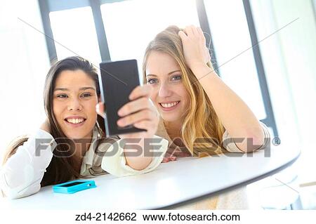 Two young women with smartphones View Large Photo Image Stock Image - Two young women with smartphones. Fotosearch