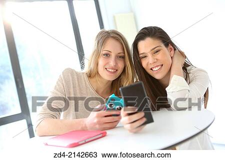 Two young women with smartphones View Large Photo Image Stock Image - Two young women with smartphones. Fotosearch