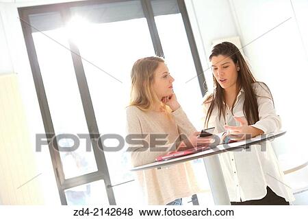Stock Photo - Two young women with smartphones. Fotosearch