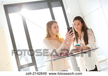 Stock Photo - Two young women with smartphones. Fotosearch