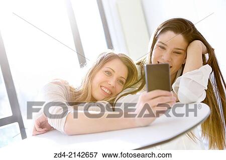 Two young women with smartphones View Large Photo Image Stock Photo - Two young women with smartphones. Fotosearch