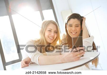 Stock Photo - Two young women with smartphones. Fotosearch