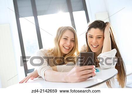 Two young women with smartphones View Large Photo Image Stock Photo - Two young women with smartphones. Fotosearch