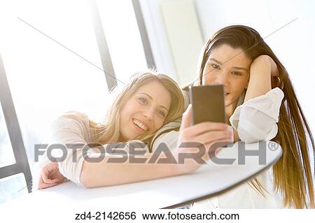 Two young women with smartphones View Large Photo Image Stock Photograph - Two young women with smartphones. Fotosearch