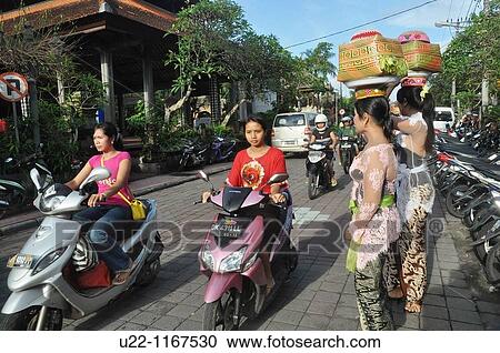 Stock Image - Ubud (Bali, Indonesia): women in traditional dress, carrying a basket with offerings on their heads, going to a ceremony in a Hindu temple. Fotosearch