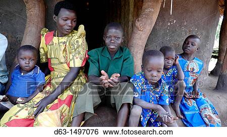 Stock Photograph - UGANDA Reformed witch-doctor Richard Ocing and his family, wife and 5 children, who gave up his practice to become a Catholic Visited by catechist Lawrence Tenga white shirt, who is responsible for bringing him back to the Church Lira. Fotosearch