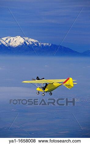 Ultra light plane flying in wintertime over thin clouds arround Torreilles At background the snowed Canigou peak 2784 m Orientales Pyrenees, Languedoc Roussillon, France View Large Photo Image Stock Photo - Ultra light plane flying in wintertime over thin clouds arround Torreilles At background the snowed Canigou peak 2784 m Orientales Pyrenees, Languedoc Roussillon, France. Fotosearch