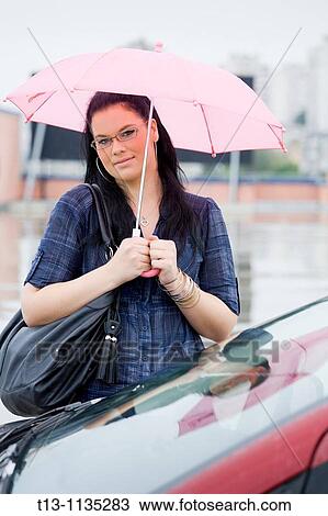 Under pink umbrella young woman is waiting next to a Red car View Large Photo Image Stock Image - Under pink umbrella young woman is waiting next to a Red car. Fotosearch