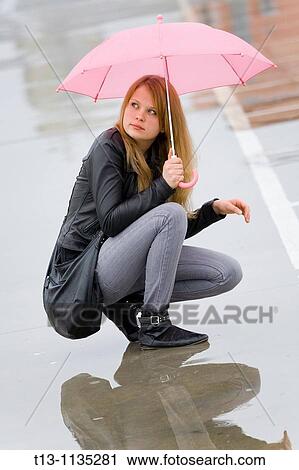 Stock Image - Under pink umbrella young woman. Fotosearch