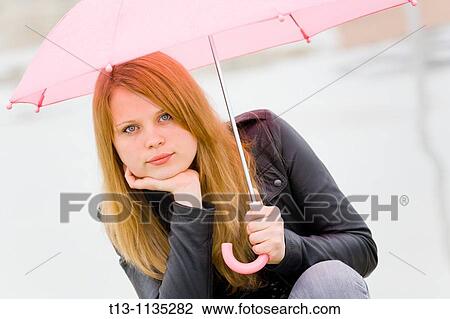 Stock Image - Under pink umbrella young woman. Fotosearch