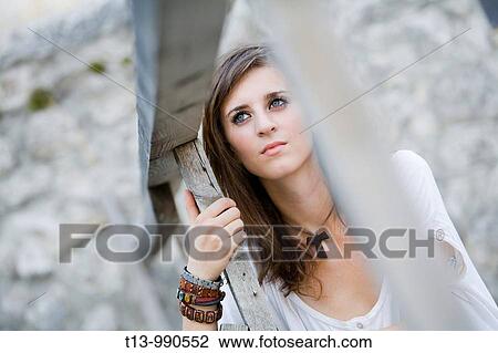 Stock Image - Under wooden fence young woman portrait. Fotosearch