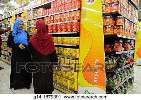 Stock Image - United Arab Emirates, U A E, UAE, Middle East, Dubai, Al Qusais, LuLu Hyper Market, shopping, grocery store, supermarket, English, Arabic, language, Asian, woman, thawb, hijab, competing brands, Nestle Nescafe, instant coffee, tea, Lipton, Red Label,. Fotosearch