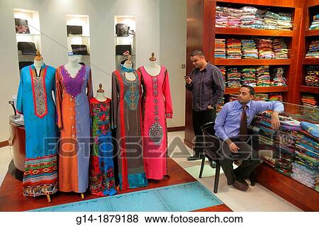 Stock Photo - United Arab Emirates, U A E, UAE, Middle East, Dubai, Downtown Dubai, Burj Dubai, Dubai Mall, shopping, fashion, store, business, clothing, women? s, Muslim, thawb, Asian, man, migrant worker, foreign laborer, retail display,. Fotosearch