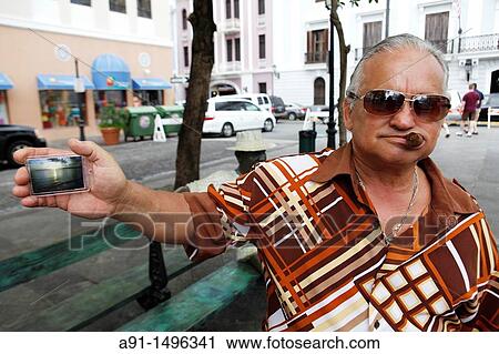 Stock Image - United States of America, Puerto Rico, San Juan the capital, senor Hector Vasquez is a cigar addict, he has taken God in picture. Fotosearch
