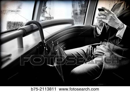 Unrecognizable businessman sitting on a double decker bus manipulating a cell phone in City of London, England, UK, Europe. View Large Photo Image Stock Image - Unrecognizable businessman sitting on a double decker bus manipulating a cell phone in City of London, England, UK, Europe.. Fotosearch