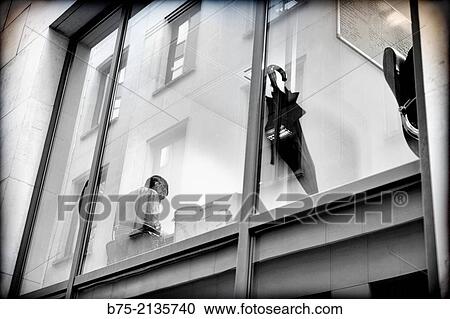 Unrecognizable Businessman working in an office seen through a window with reflections in the glass and an umbrella in the foreground in The City of London, England, UK, Europe View Large Photo Image Stock Image - Unrecognizable Businessman working in an office seen through a window with reflections in the glass and an umbrella in the foreground in The City of London, England, UK, Europe. Fotosearch