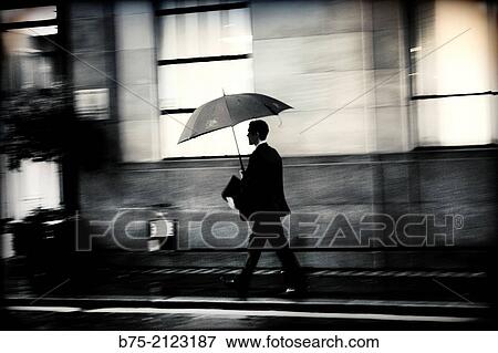 unrecognizable executive with portfolio and under an umbrella in the evening walking in the street in London, England, UK, Europe View Large Photo Image Stock Photo - unrecognizable executive with portfolio and under an umbrella in the evening walking in the street in London, England, UK, Europe. Fotosearch