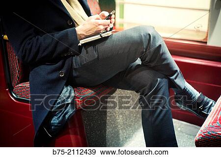 Unrecognizable man seating in the bus with a note book manipulating a cell phone. London, England, UK, Europe. View Large Photo Image Stock Photo - Unrecognizable man seating in the bus with a note book manipulating a cell phone. London, England, UK, Europe.. Fotosearch