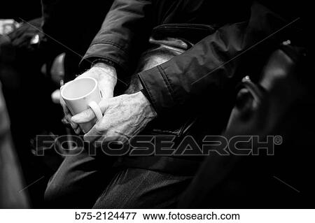 Stock Photo - Unrecognizable man sitting at a bar with a cup of coffee in hand in London, England, UK, Europe.. Fotosearch