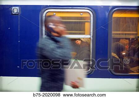 Unrecognizable young man in motion, walking and talking on the phone on the platform of a Paris metro station, France View Large Photo Image Stock Photo - Unrecognizable young man in motion, walking and talking on the phone on the platform of a Paris metro station, France. Fotosearch