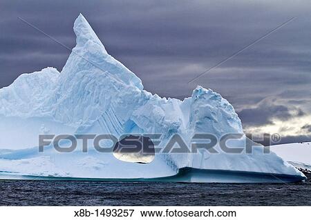 Unusual window formation in iceberg with Booth Island in the background on the western side of the Antarctic Peninsula during the summer months, Southern Ocean View Large Photo Image Stock Photo - Unusual window formation in iceberg with Booth Island in the background on the western side of the Antarctic Peninsula during the summer months, Southern Ocean. Fotosearch