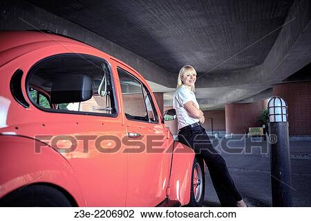 Stock Image - urban portrait of a young woman with a classic car.. Fotosearch