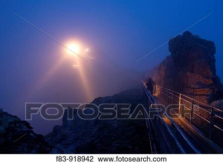 Stock Image - USA, California, Marin County, Point Reyes National Seashore, lighthouse and staircase in fog at dusk, person on stairs. Fotosearch