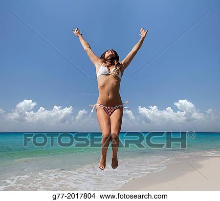 Picture - Usa. Florida. Miami Beach. Woman jumping on a beach.. Fotosearch